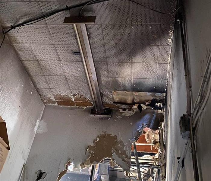 Damaged ceiling and wall in a storage room of a business after neighboring fire